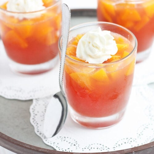 individual serving of peach jello salad topped with whipped cream