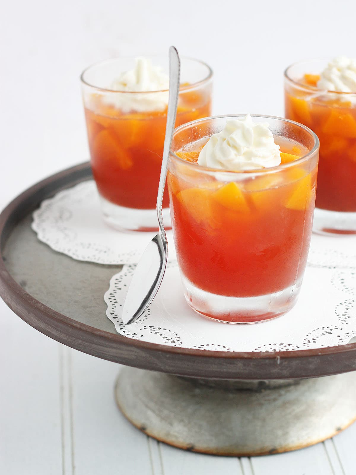 three individual servings of peach jello salad topped with whipped cream