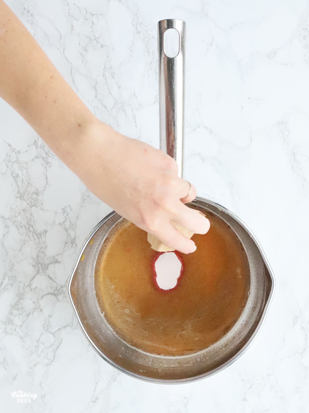 hand pouring peach gelatin into a saucepan