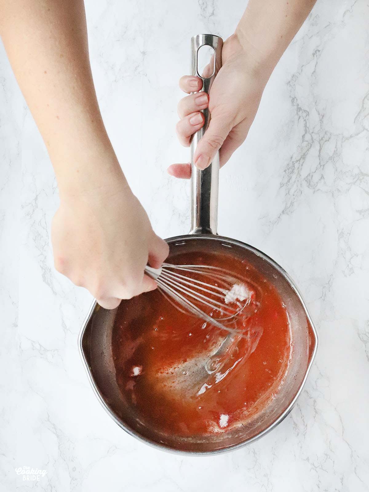 hand whisking peach gelatin into saucepan
