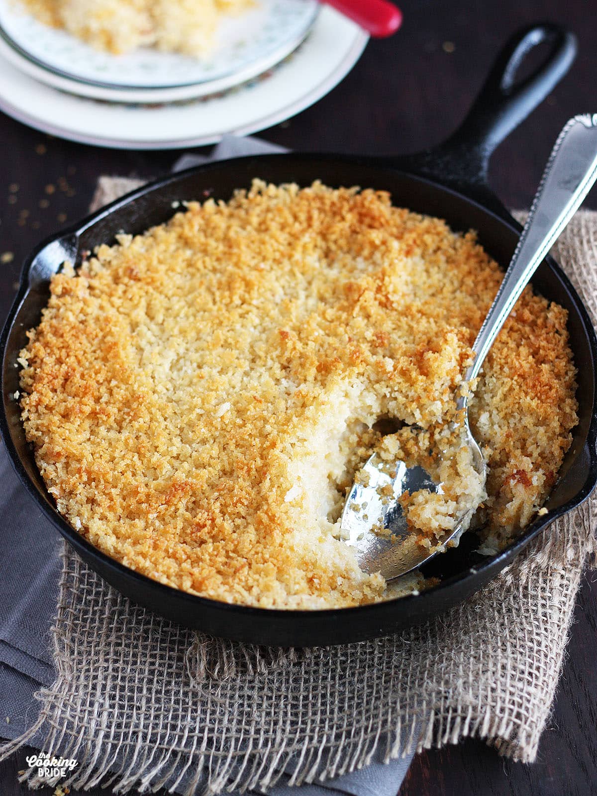 cauliflower gratin in a cast iron skillet with a serving spoon
