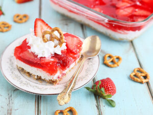 one serving of strawberry pretzel salad on a plate garnished with whipped cream