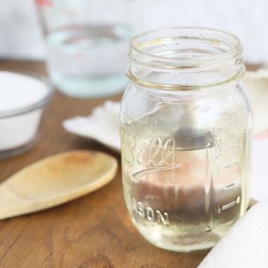 mason jar full of simple syrup with sugar and water in the background