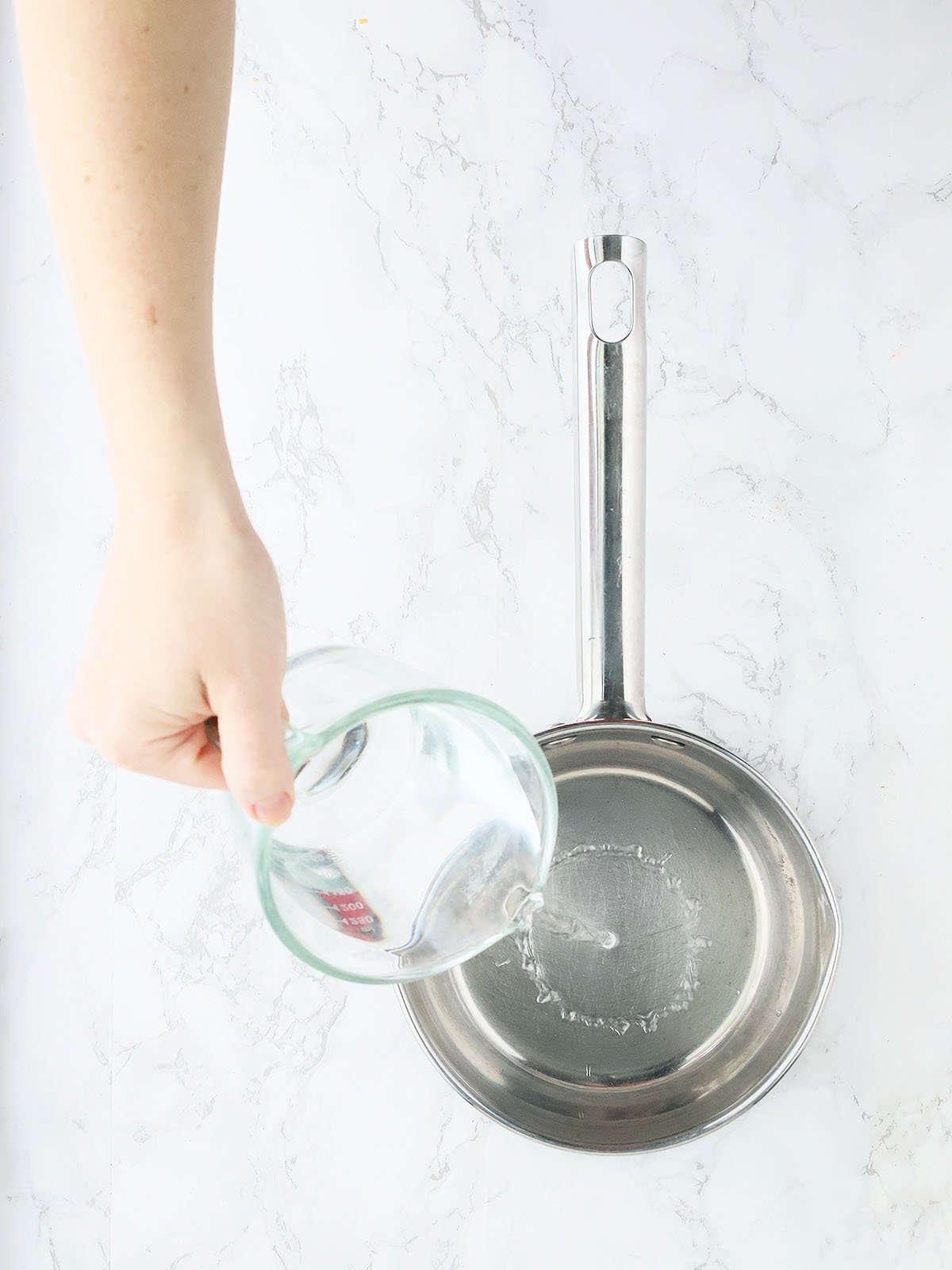 pouring water into a stainless steel saucepan