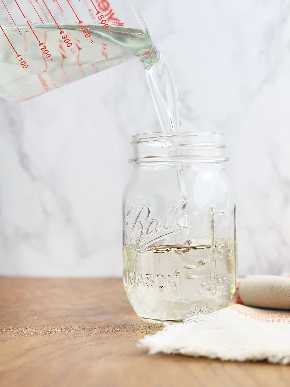 pouring cooled simple syrup into a Mason jar