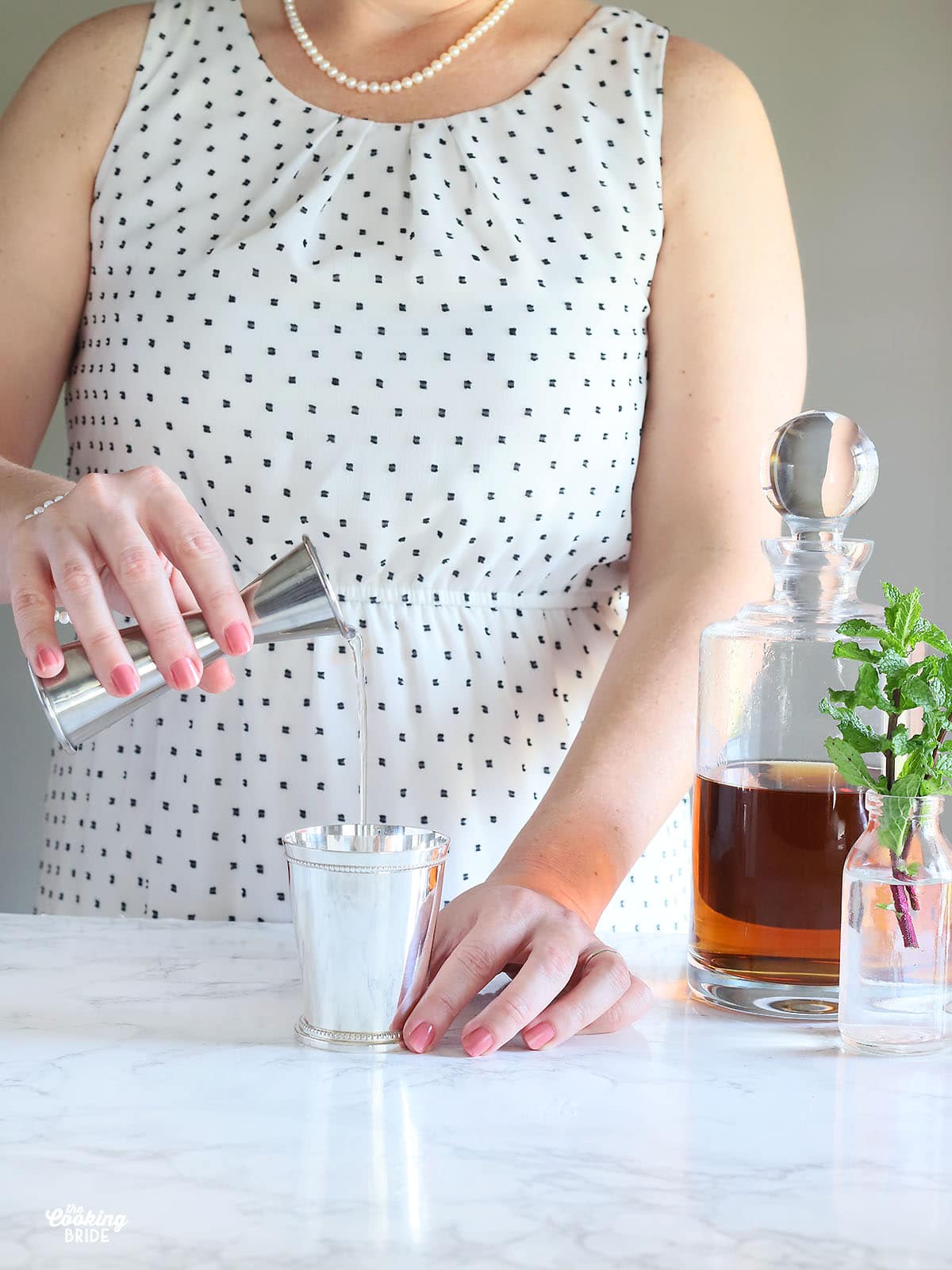 pouring simple syrup into a mint julep cup