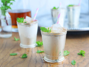 two silver mint julep cups on a wooden background