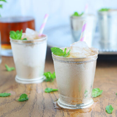 two silver mint julep cups on a wooden background