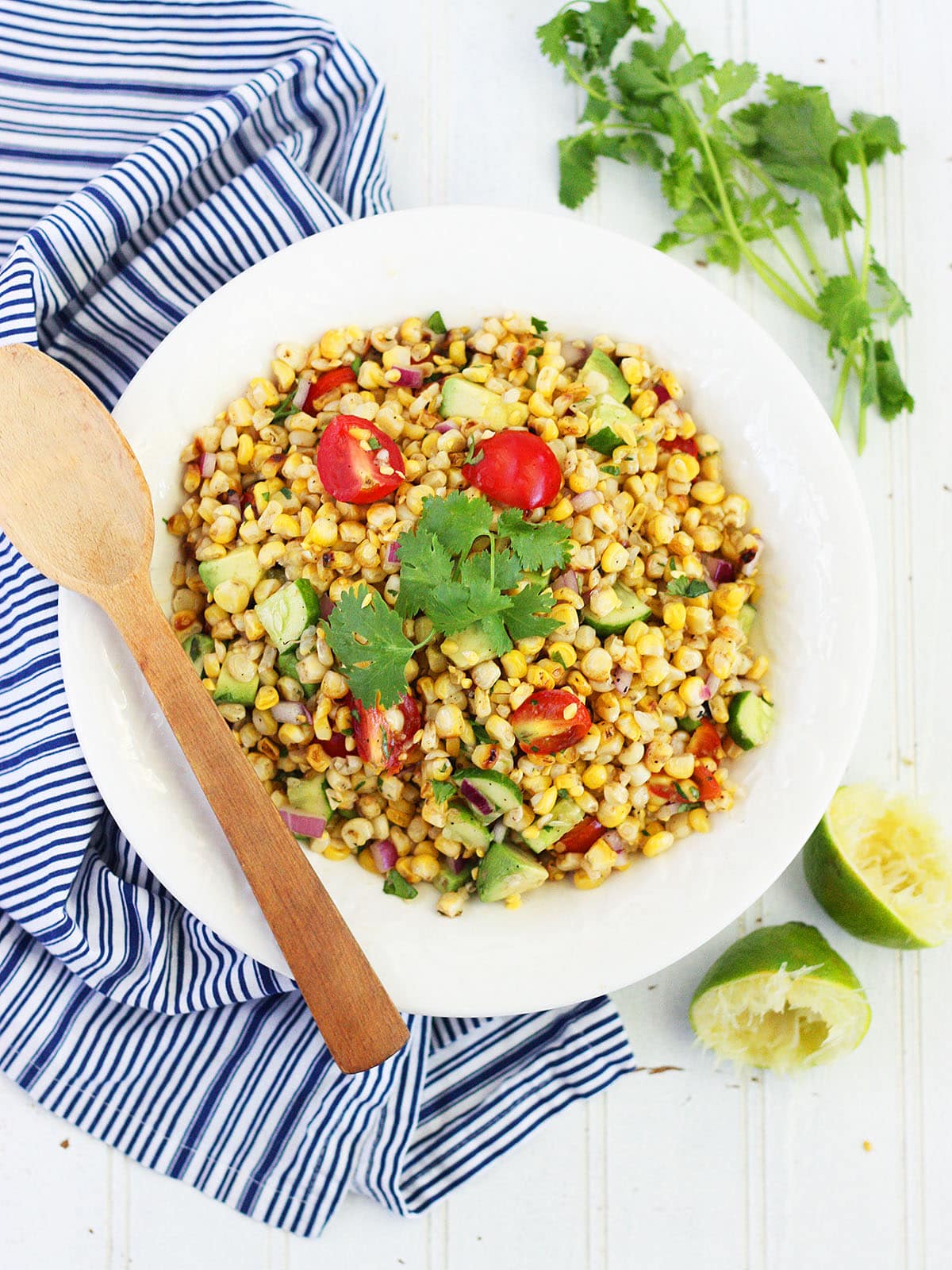 roasted corn salad in a white serving bowl garnished with a sprig of cilantro