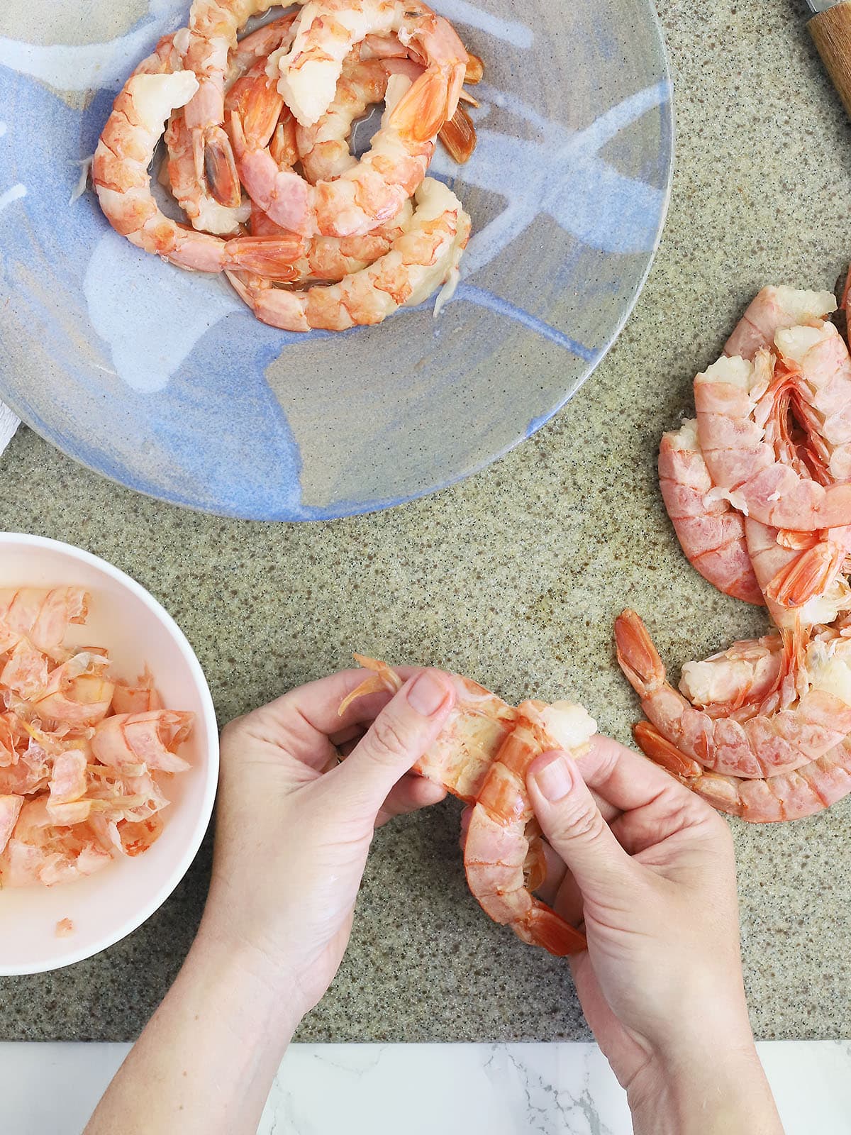 hands peeling off the shells and legs of a shrimp