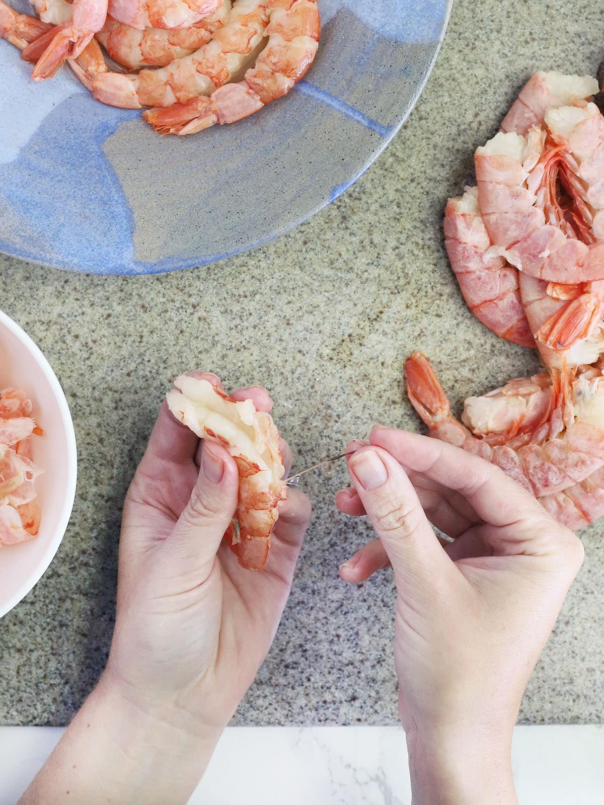 hand pulling out and removing the sand vein from a peeled shrimp