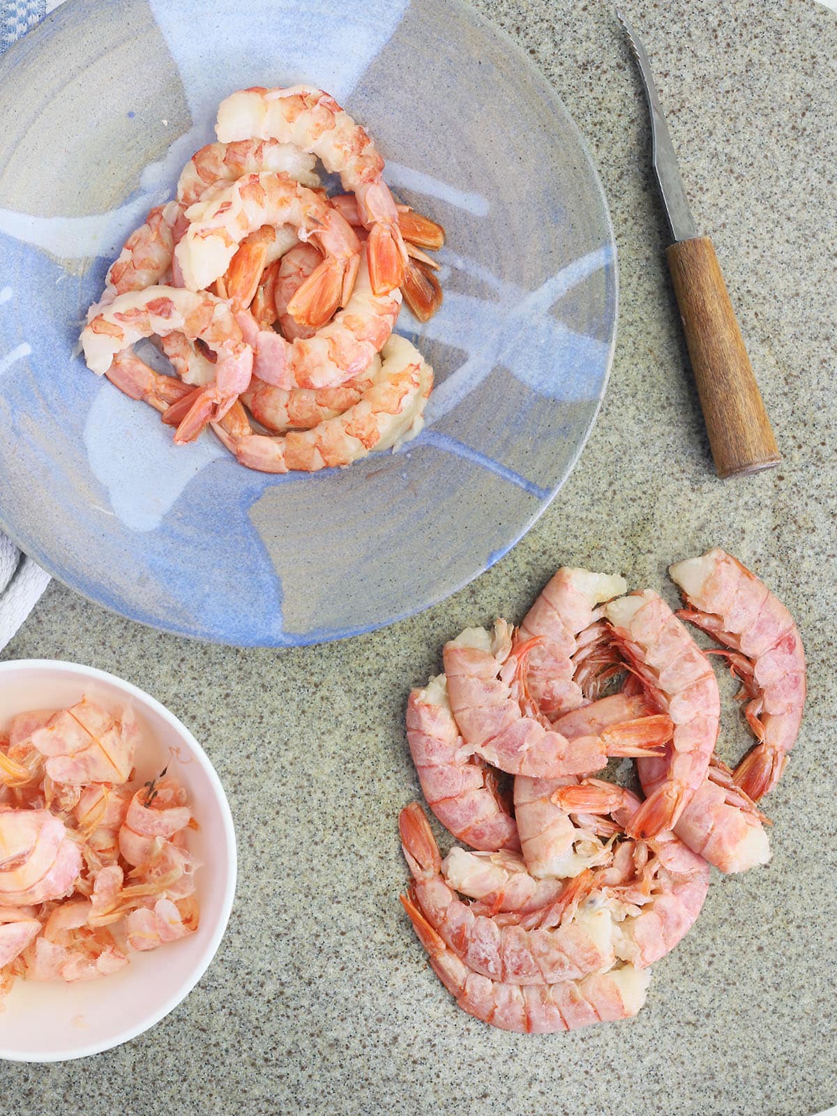 shrimp in the process of being peeled and deveined on al gray stone cutting board