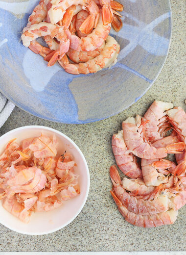 shrimp in the process of being peeled and deveined on al gray stone cutting board