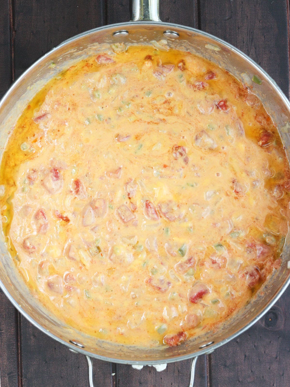 melted cheese, rotel tomatoes and vegetables in a large stainless steel skillet