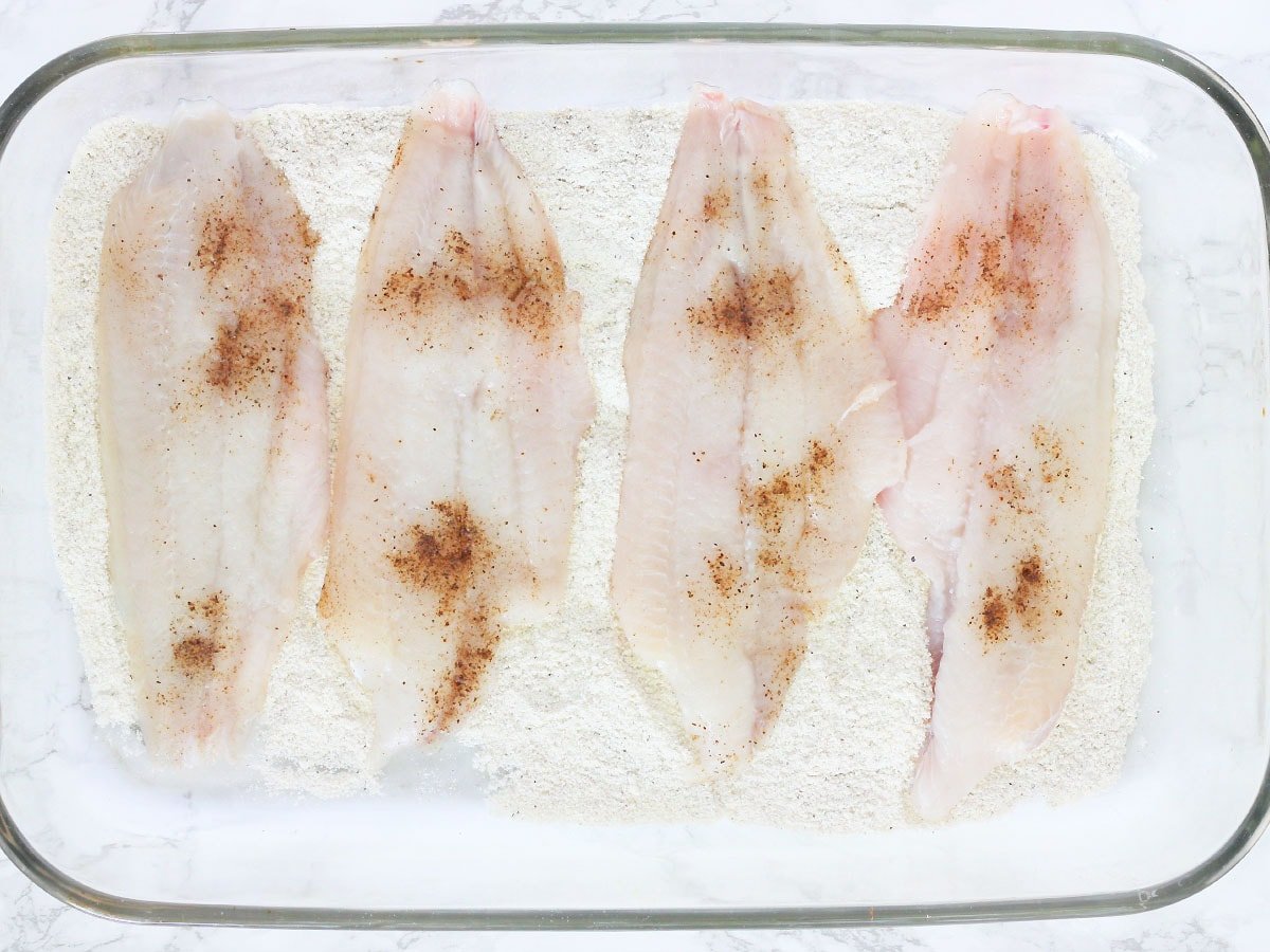 catfish fillets laying in a dish of cornmeal