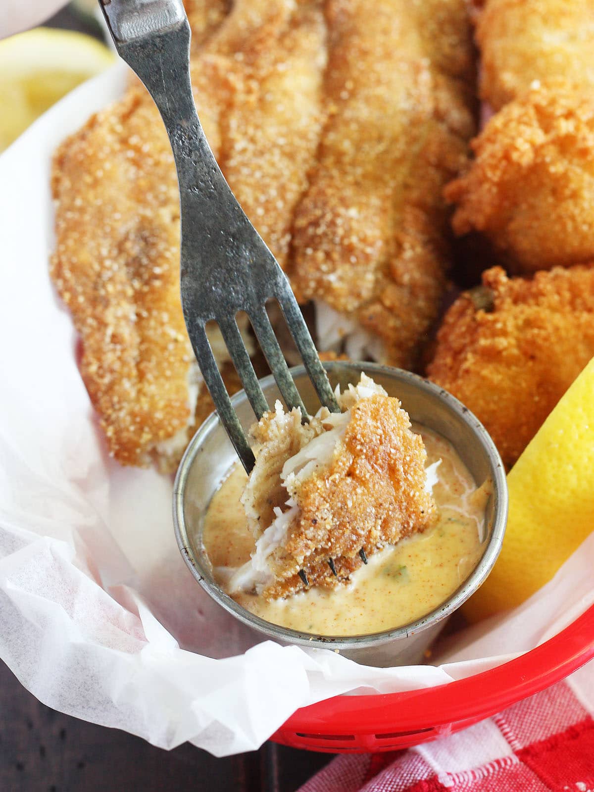 forkful of fried catfish being dipped in remoulade sauce