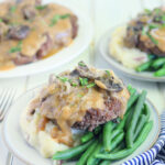 hamburger steak served over mashed potatoes and green beans covered in mushroom gravy