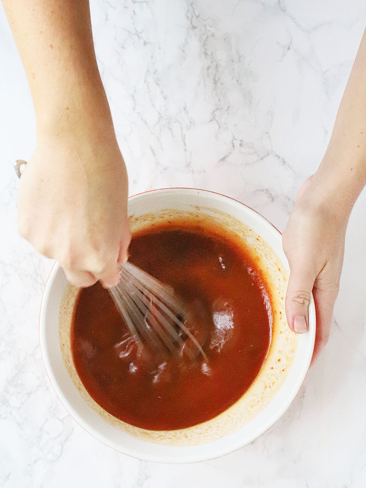 hands whisking together the bourbon apricot glaze ingredients