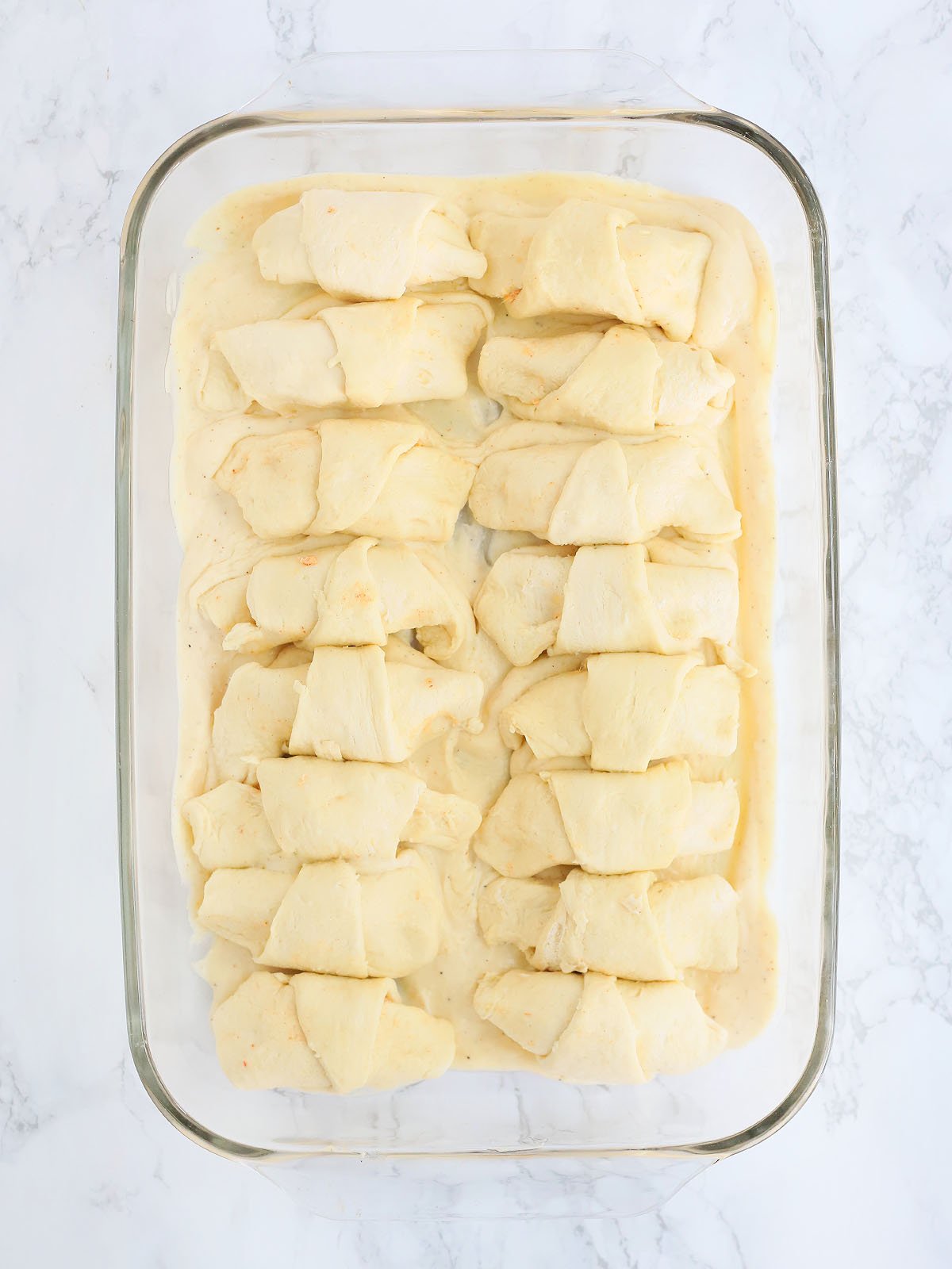 unbaked stuffed and rolled crescents arranged over gravy in a glass casserole dish