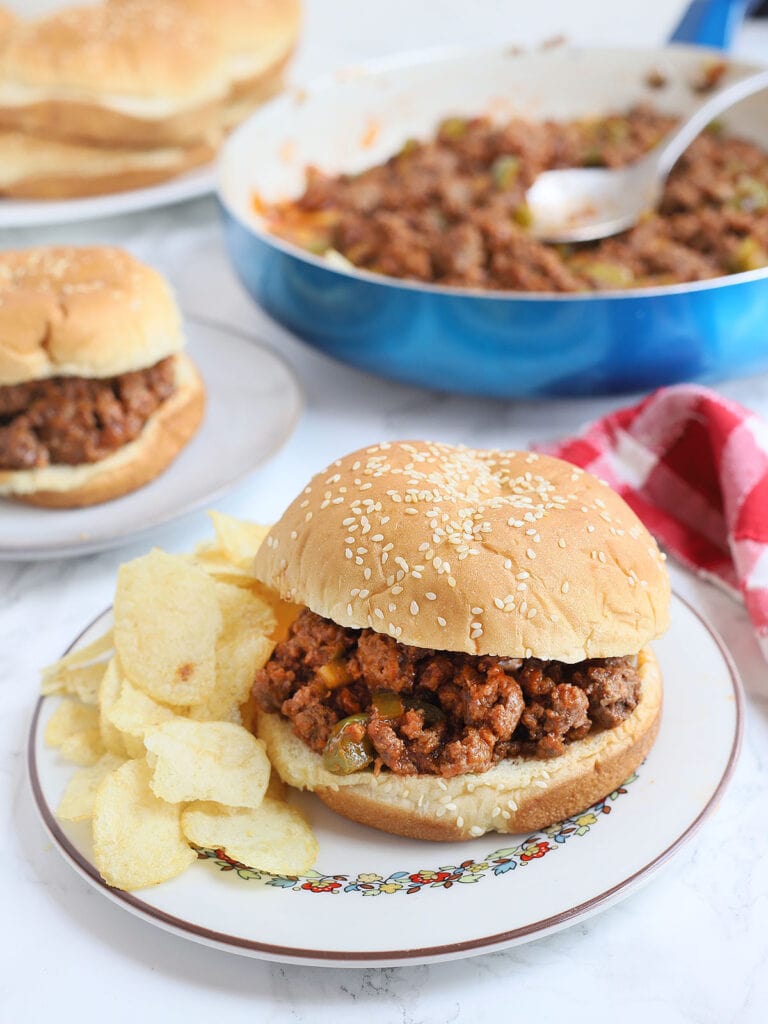 Sloppy Joe sandwich on a plate with chips on the side