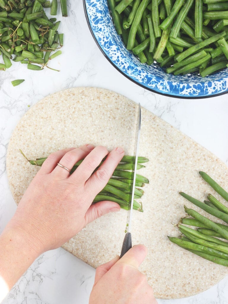 Hand cutting the stem end off a bunch of green beans.