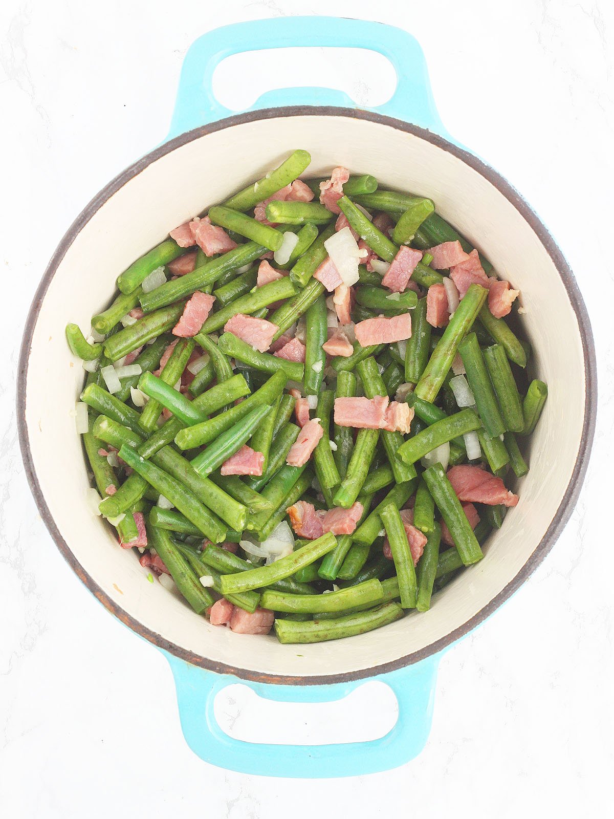 sauteing the green beans with the onion and ham