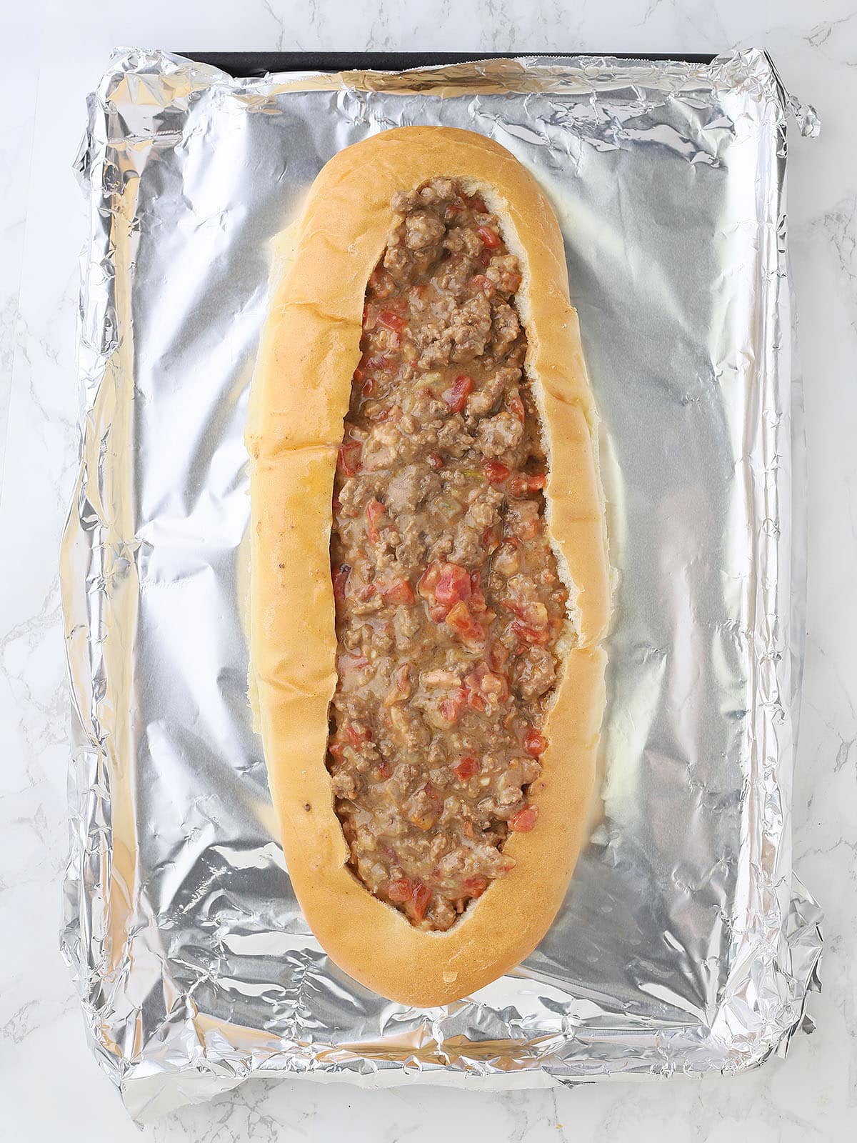 hollowed out French bread loaf filled with the cheeseburger mixture