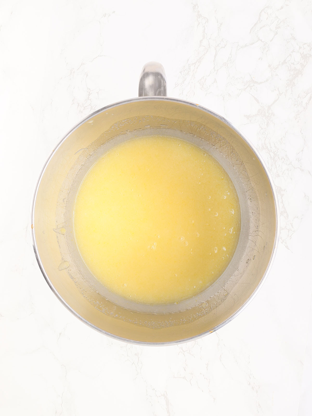 eggs, oil and sugar mixed together in a metal mixing bowl