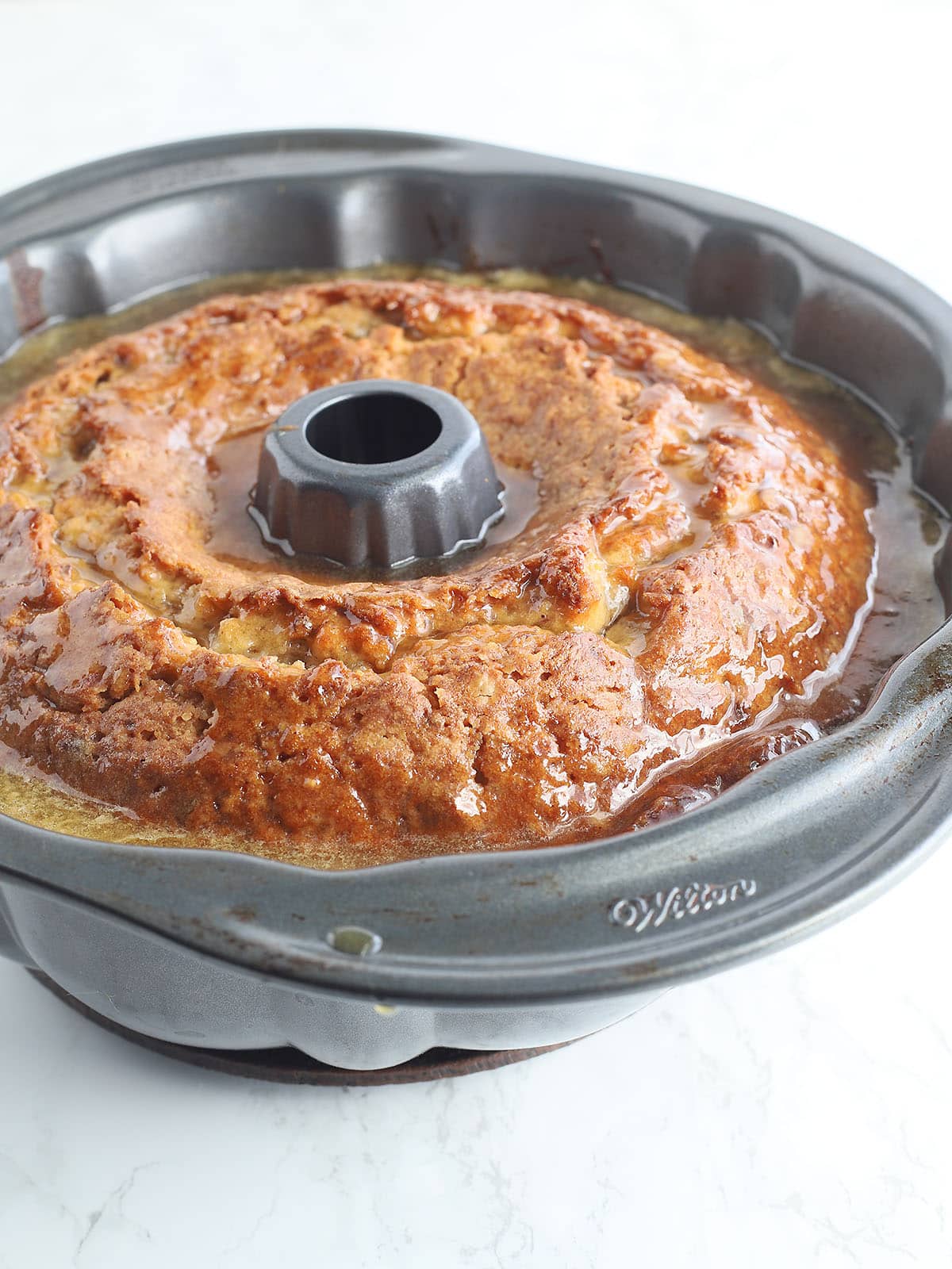 apple dapple cake in a Bundt pan with glaze poured over the top