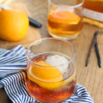 two bourbon old fashioned cocktails on a blue and white napkin