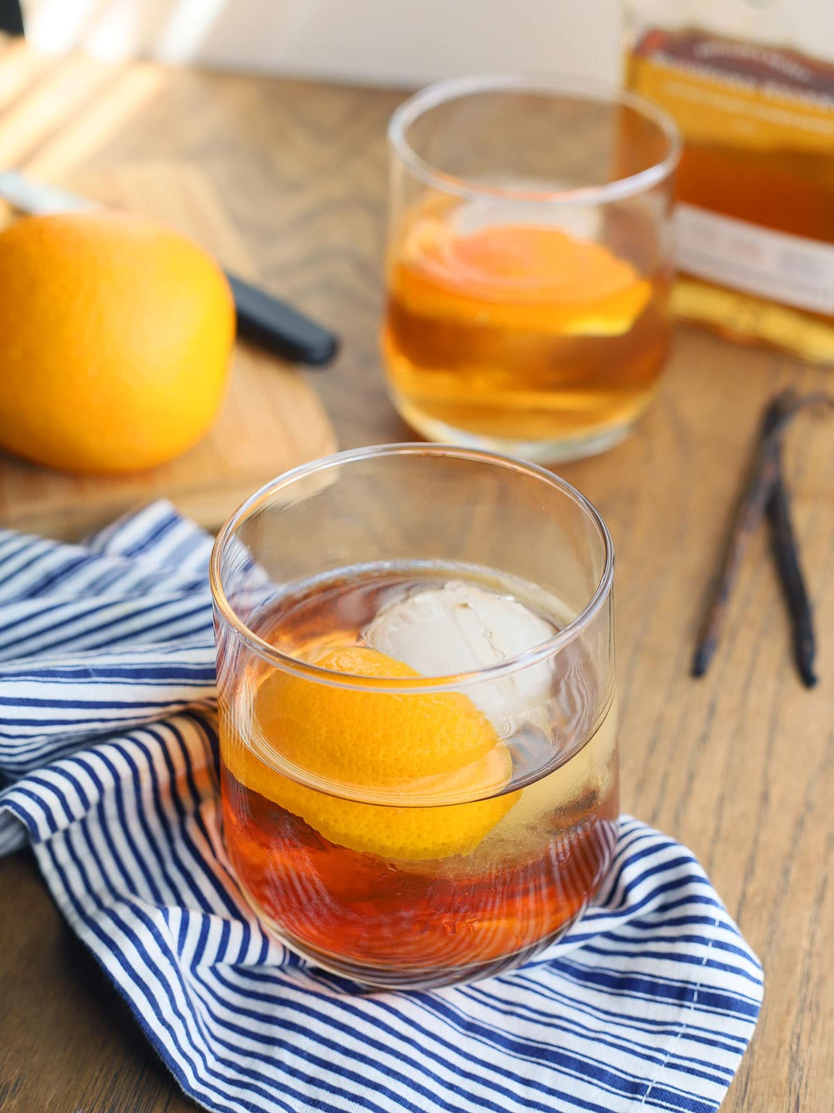 two bourbon old fashioned cocktails on a blue and white napkin
