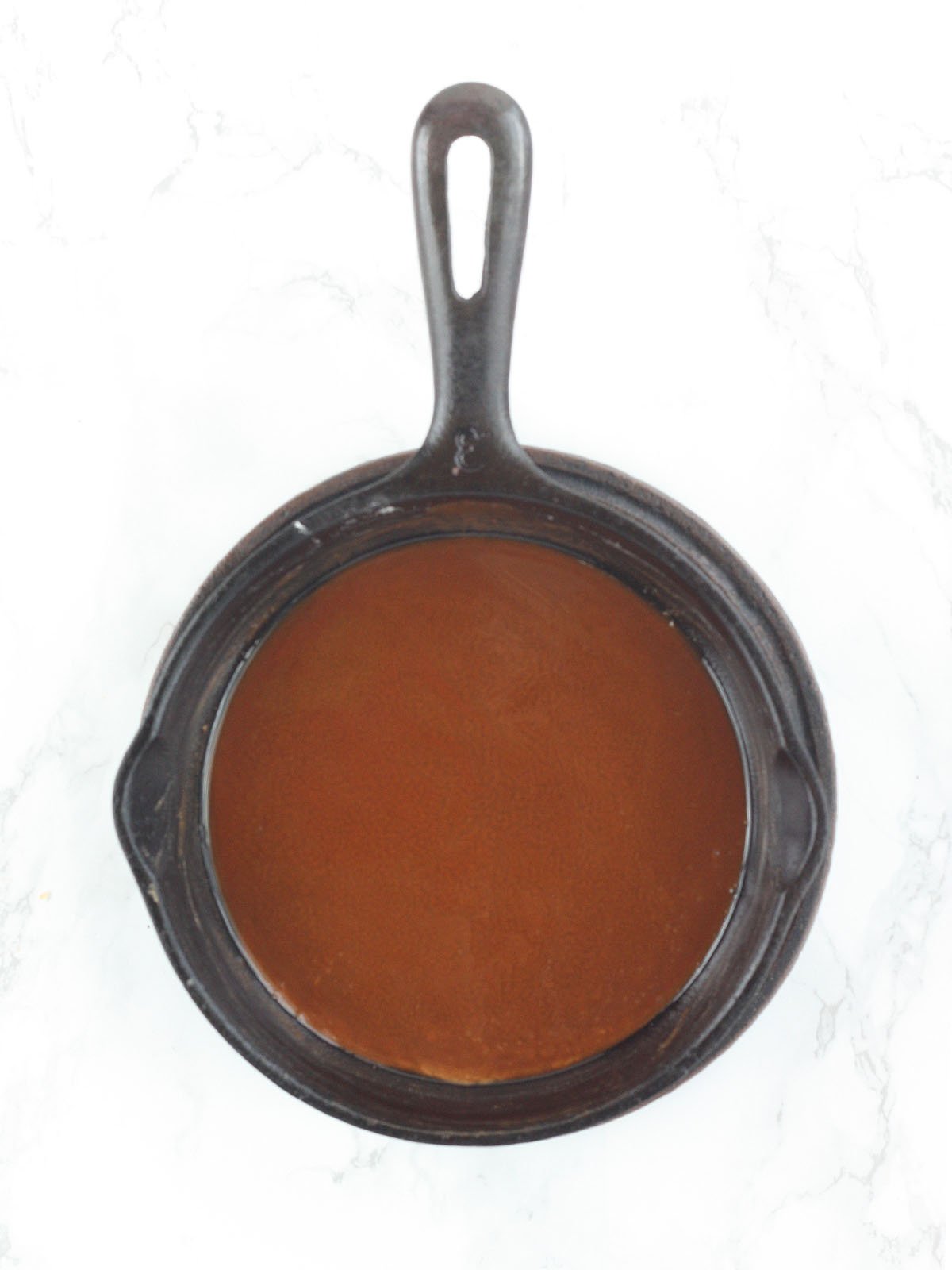 Dark brown roux in a cast iron skillet.
