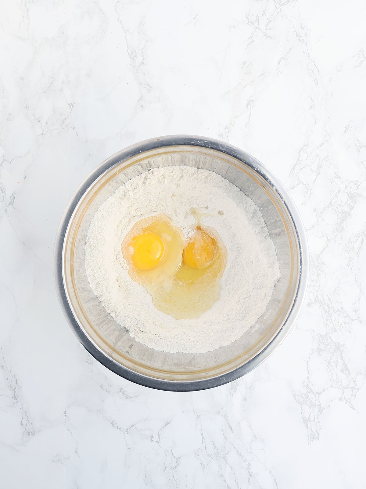cornmeal with two large eggs in a metal mixing bowl