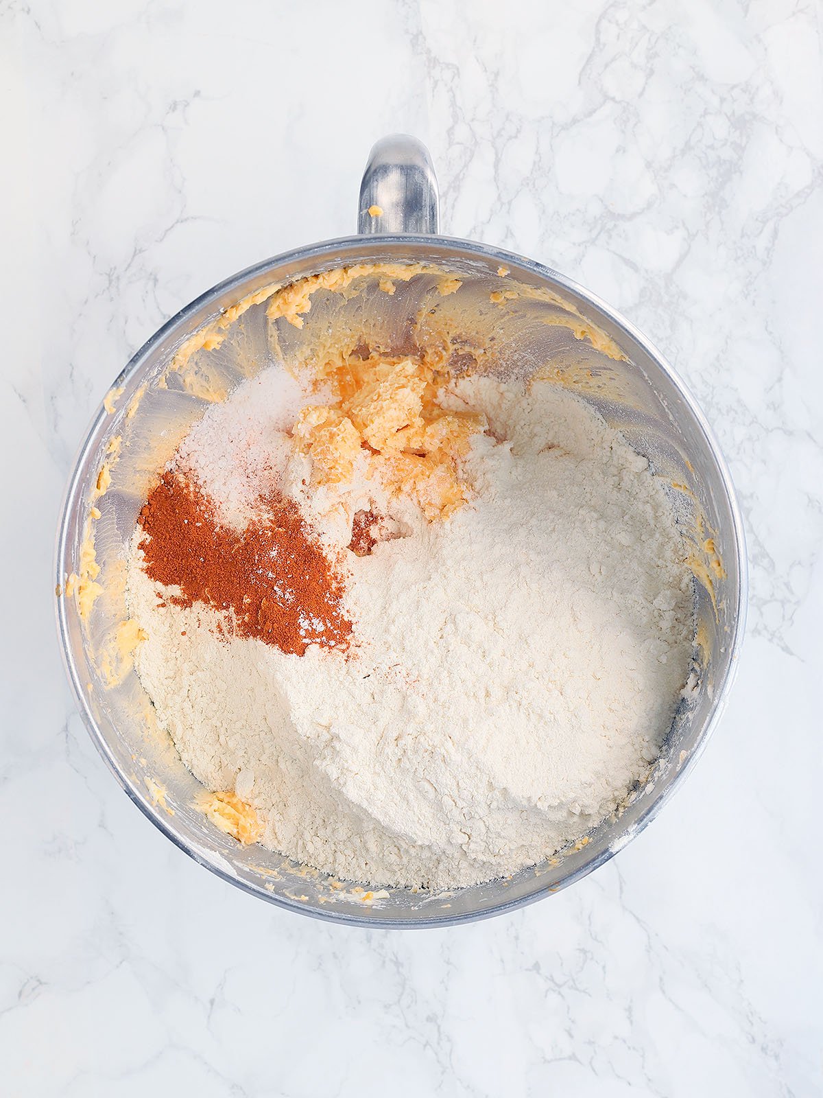 flour, salt and cayenne pepper added to the cheese mixture in a metal mixing bowl.