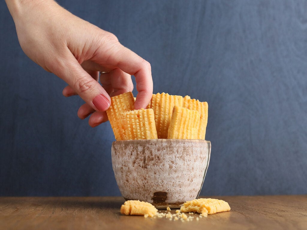 hand removing a cheese straw from a bowl