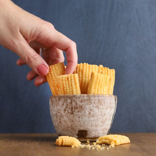 hand removing a cheese straw from a bowl