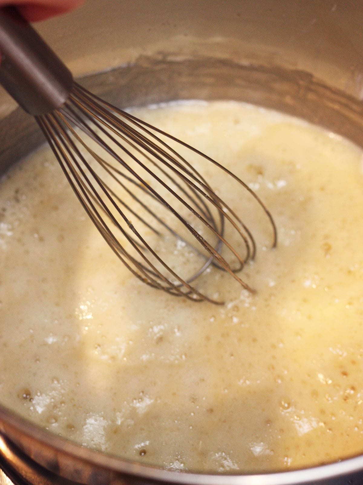 Metal whisk mixing in flour into the oil.