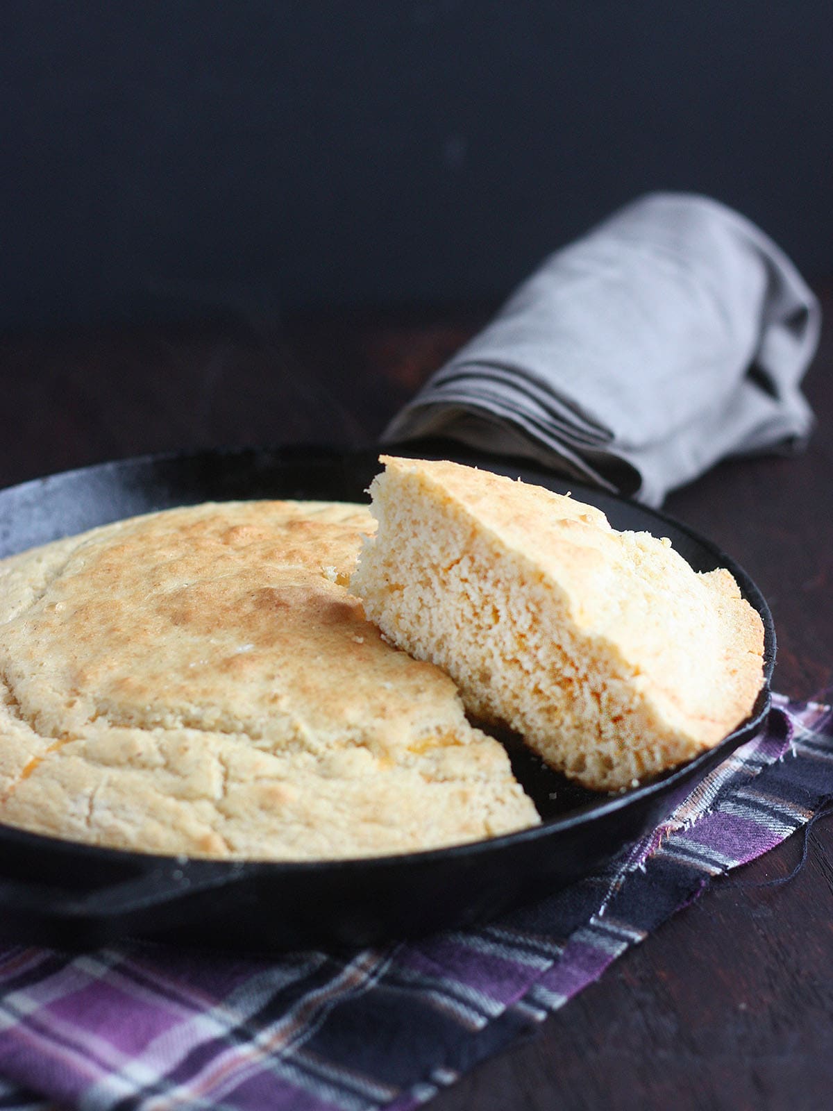 slice of cornmeal cut out and resting on top of a pan of cornbread