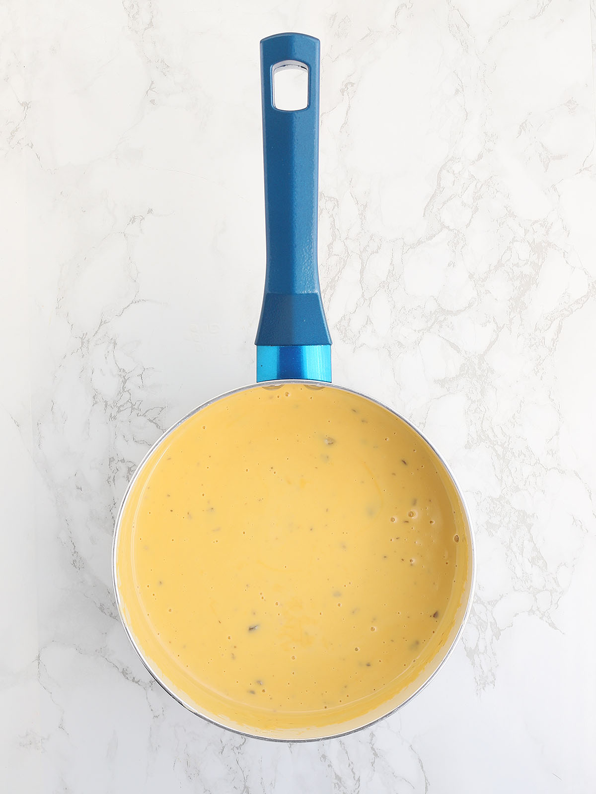 melted cheese sauce in a blue saucepan