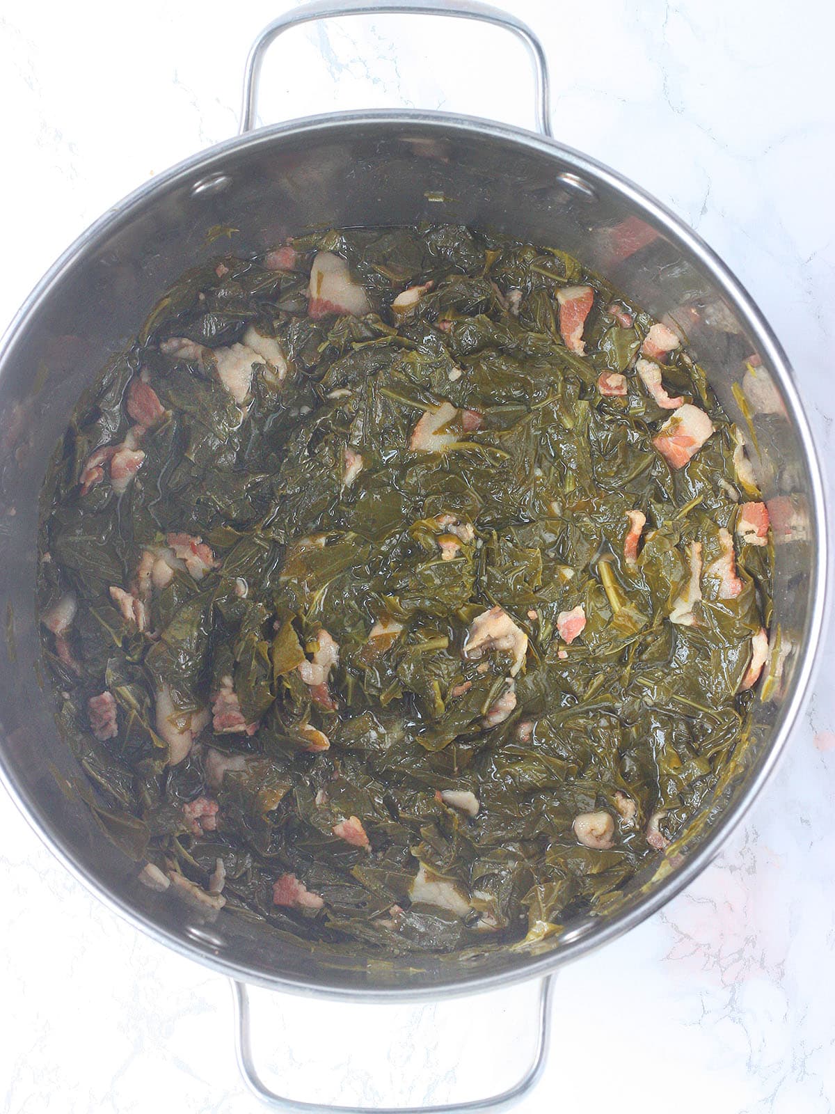 Cooked turnip greens in a stainless steel pot.