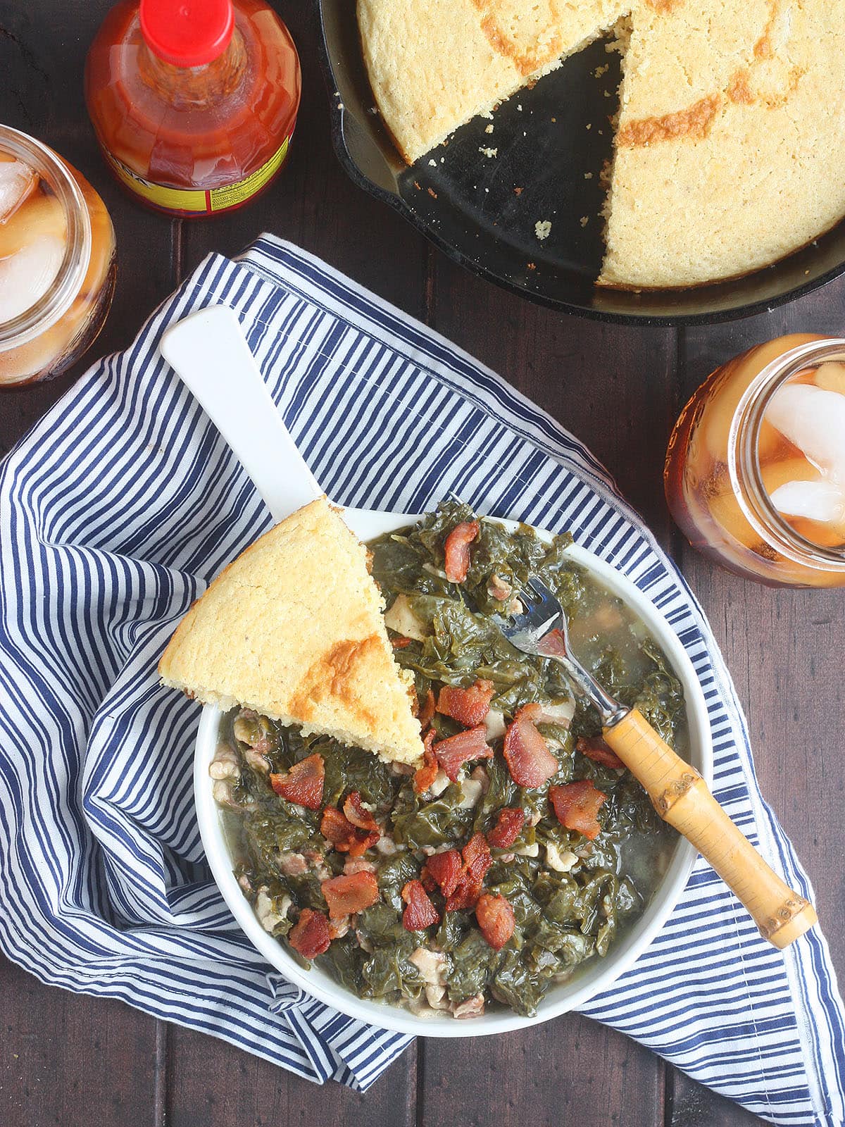 Turnip greens in a white bowl with a wedge of cornbread on the side.