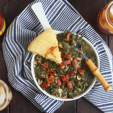 turnip greens in a white bowl with a wedge of cornbread on the side