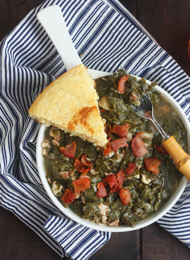 turnip greens in a white bowl with a wedge of cornbread on the side
