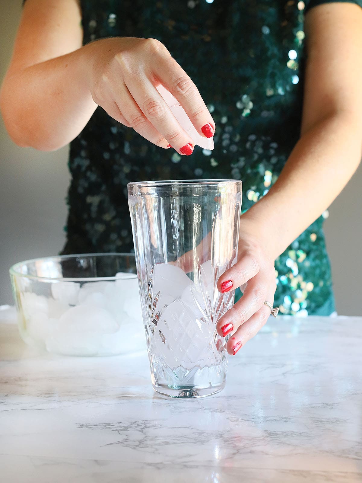 hands adding ice to a cocktail shaker