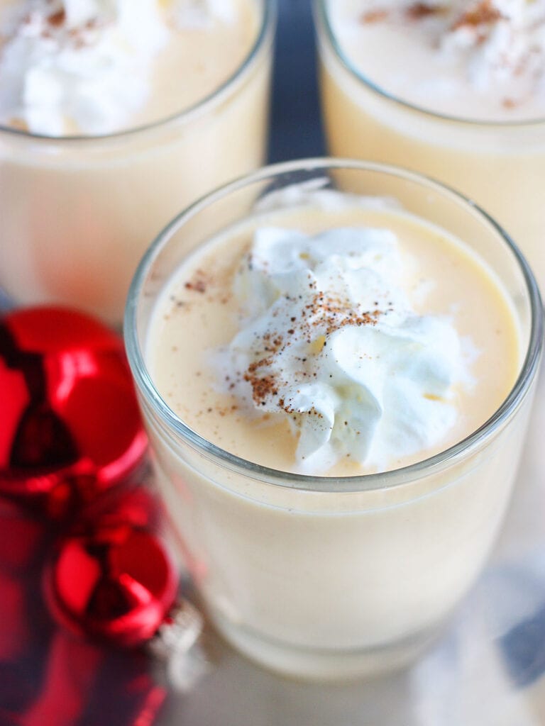 glass of bourbon eggnog garnished with whipped cream and nutmeg