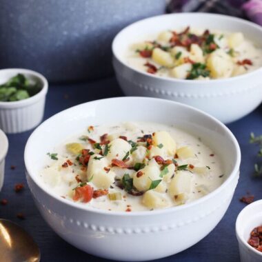 old fashioned potato soup in a white bowl garnished with chopped bacon bits and parsley