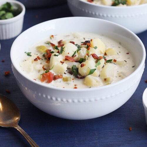 Old-fashioned potato soup in a white bowl garnished with chopped bacon bits and parsley.