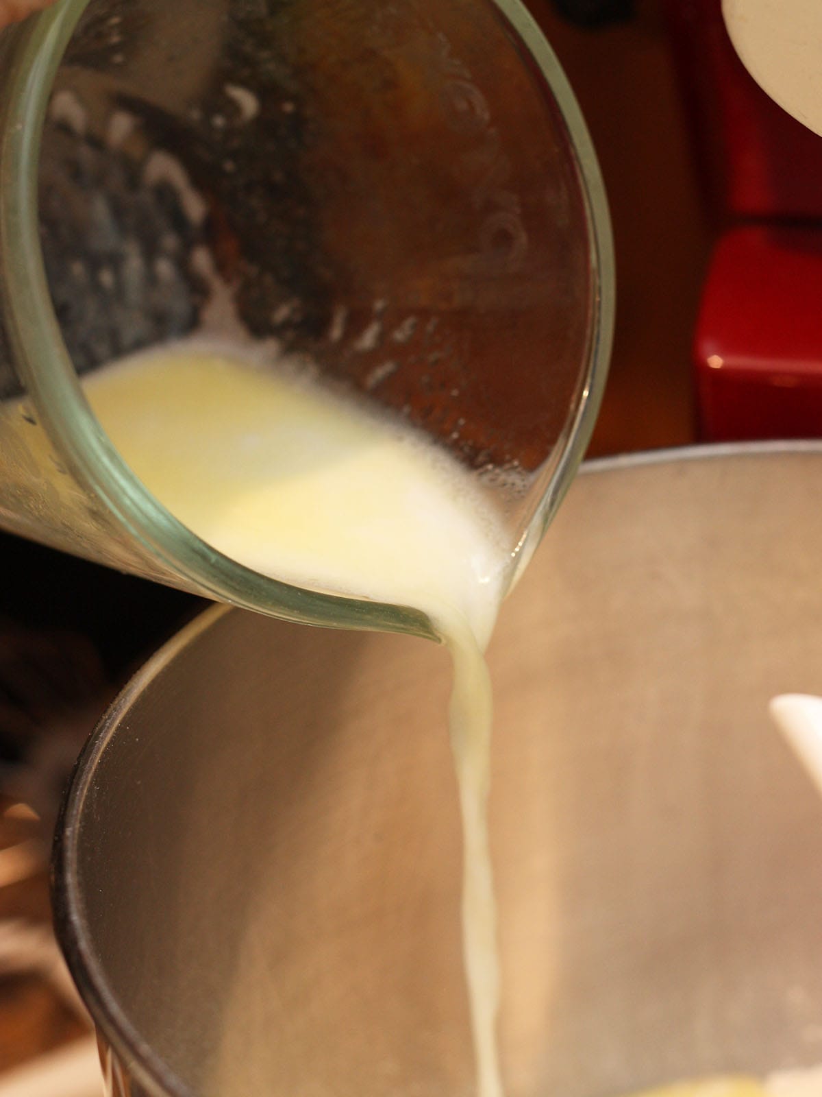 pouring melted butter and warm milk into the mixing bowl with the flour and sugar