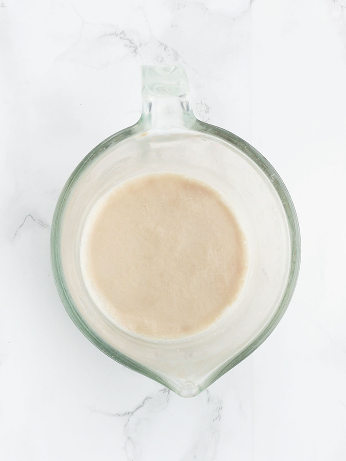 activated yeast with foam on top in a glass measuring cup