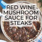 pan of red wine mushroom sauce for steak with two steaks and a glass of red wine on the side.